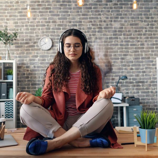 Woman practicing a calm yoga pose near her office desk.